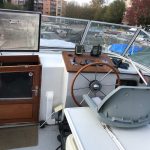 Photo du poste de pilotage extérieur accessible via une petite échelle blanche. Le poste de pilotage est également de couleur blanche et se situe sur la grande terrasse en bois gris.