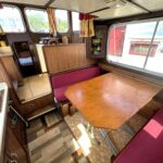 Pénichette Locaboat 930 Sérénité (1981) – Salon mit Tisch und weinroten Sitzbänken