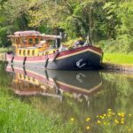 Niederländisches Hagenaar-Schiff 18 m ANNA (1911) – Außenansicht auf einem baumgesäumten Kanal